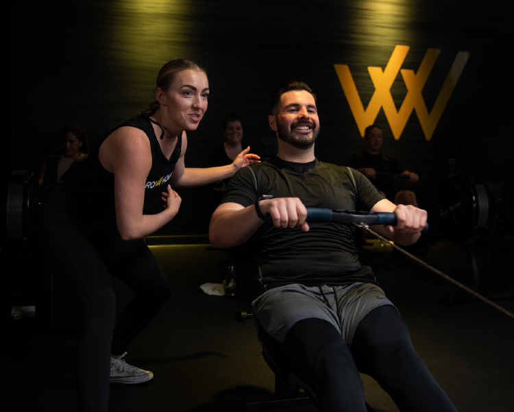 Woman instructing member on rowing machine