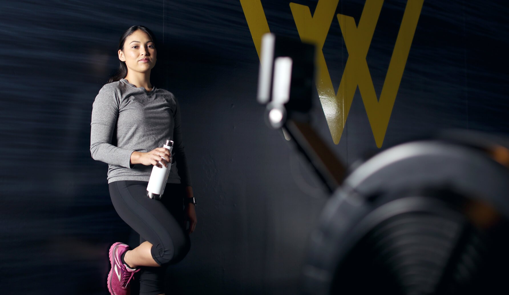 Person holding a water bottle and leaning against a wall at Row House